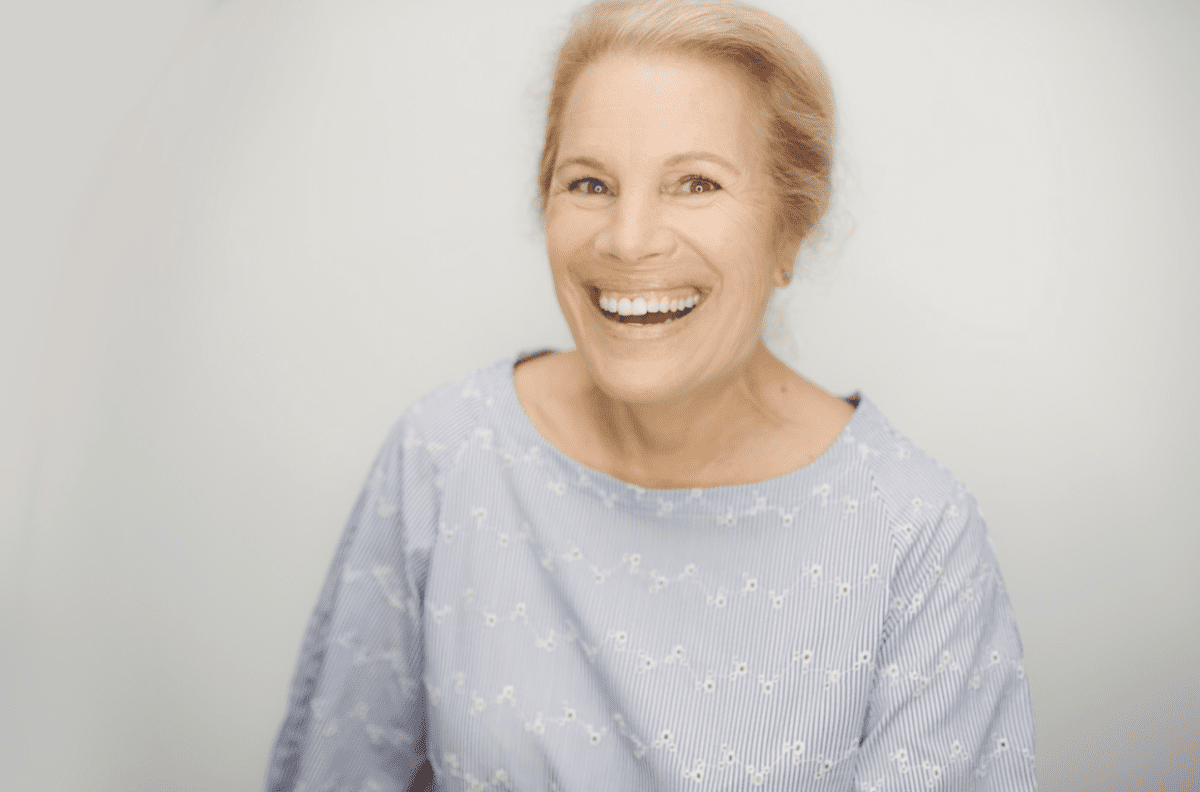 An older woman wearing a grey sweatshirt and smiling