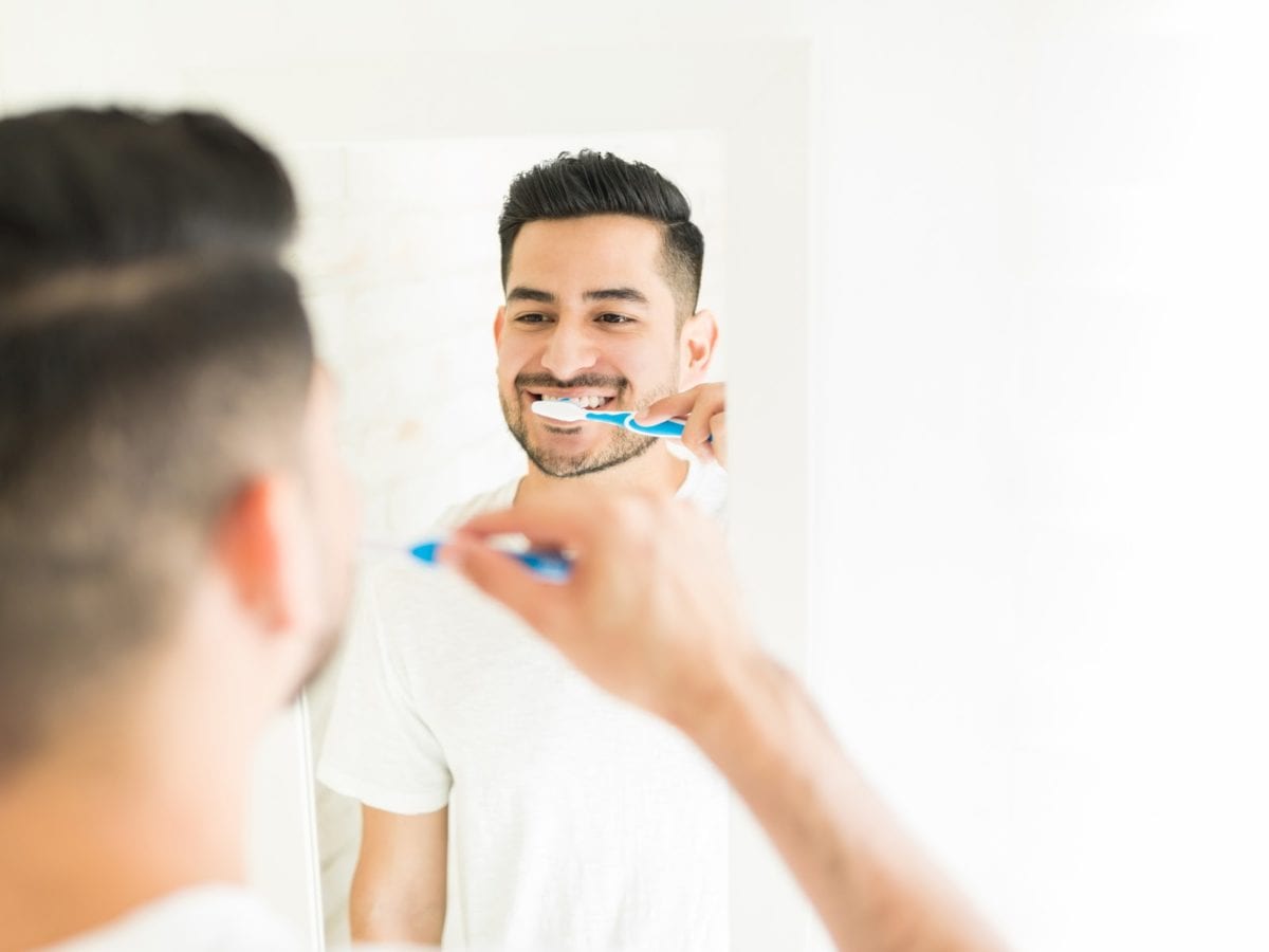 Young man brushing his teeth illustrating how to care for your smile post-braces