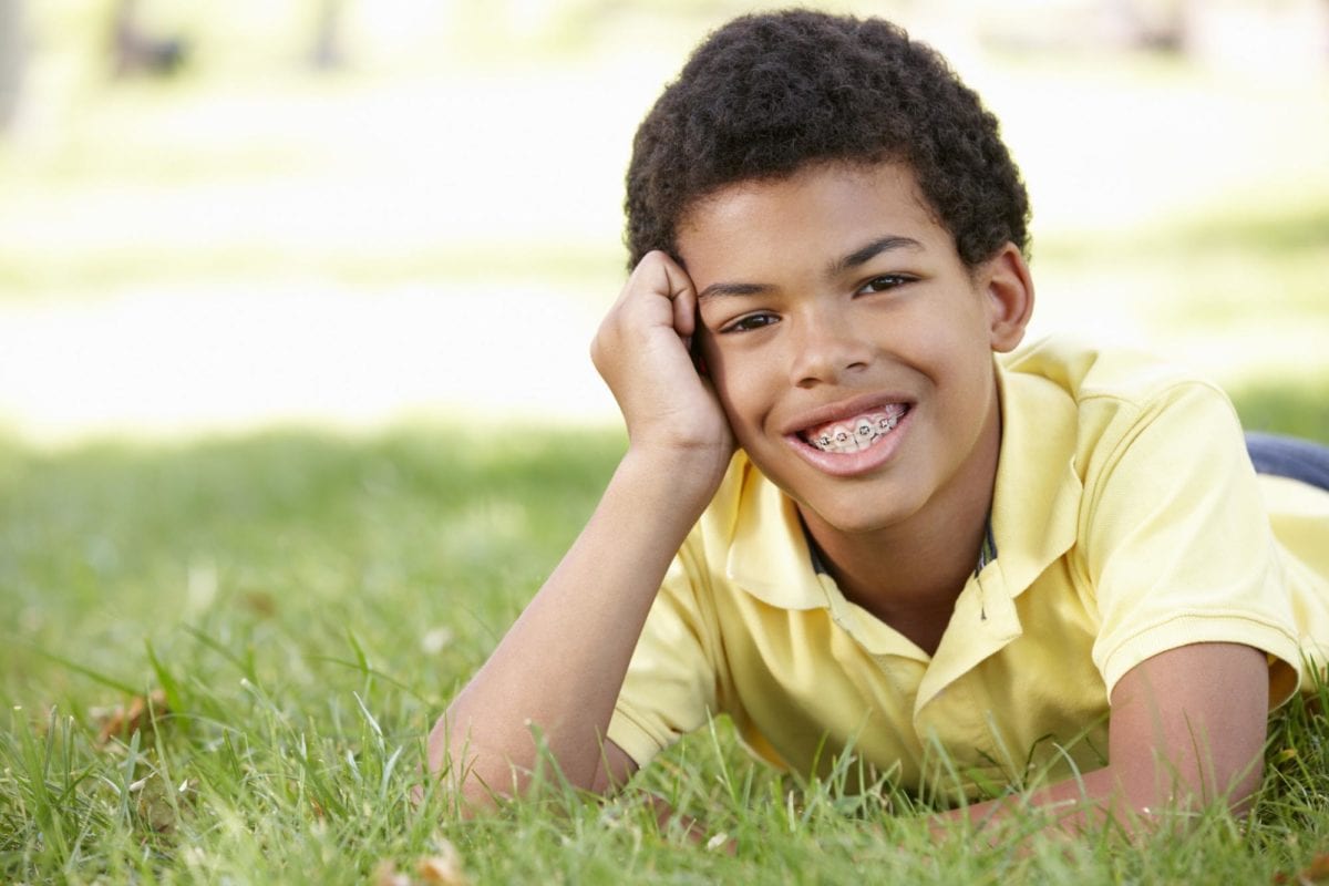 Young boy with braces lying on the grass smiling